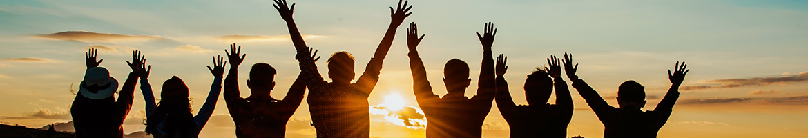 Silhouette of several people looking out the sun with their hands outstretched